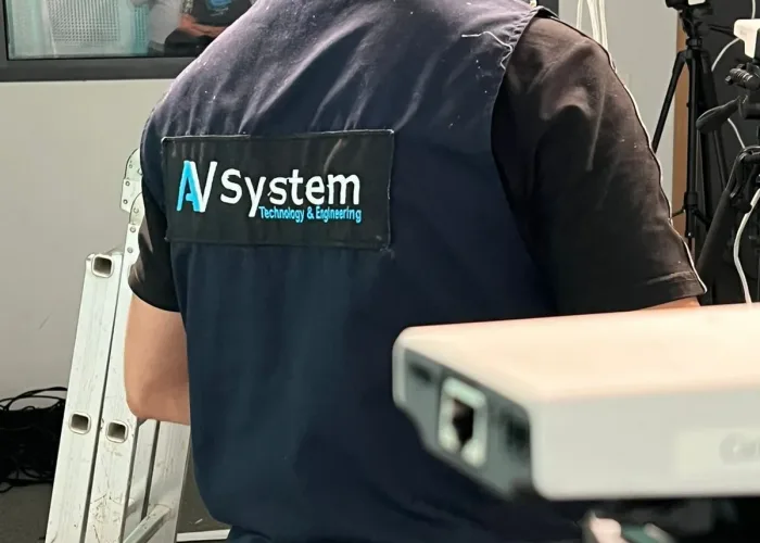 Technicien d'AV SYSTEM en train de configurer des équipements audiovisuels pour un événement, assurant une installation professionnelle.