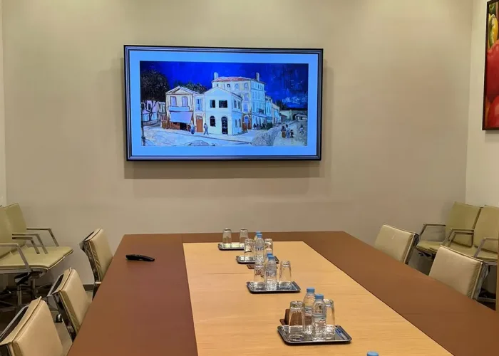 Grande salle de réunion moderne avec équipement audiovisuel d'AV SYSTEM, comprenant une table centrale, des chaises ergonomiques et un écran de projection.